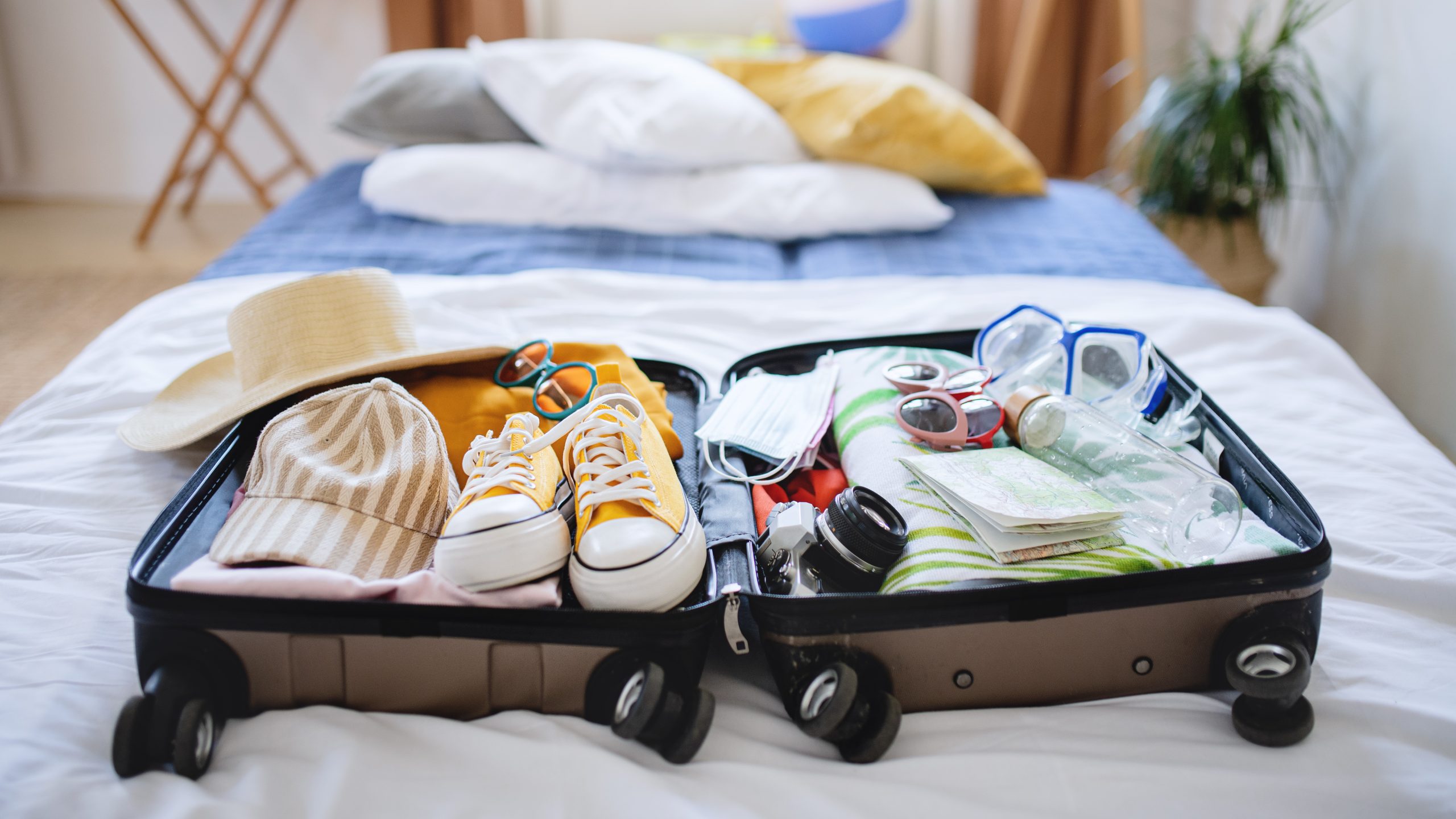 Open suitcase packed for holiday on bed at home