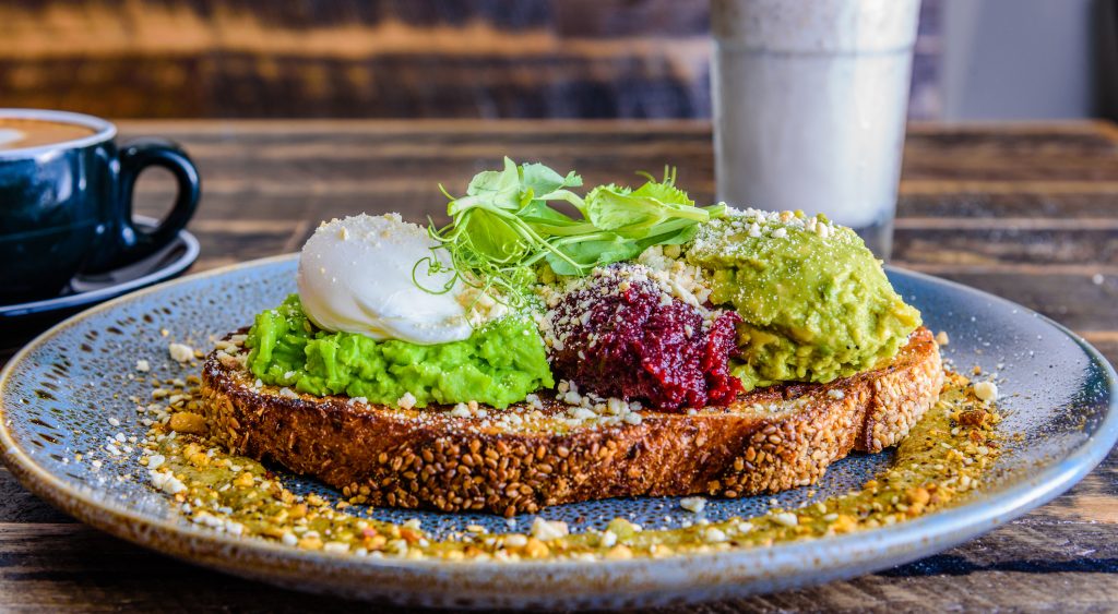 Acplate of smashed avocado on toast with a poached egg on top - A Way To Go Travel